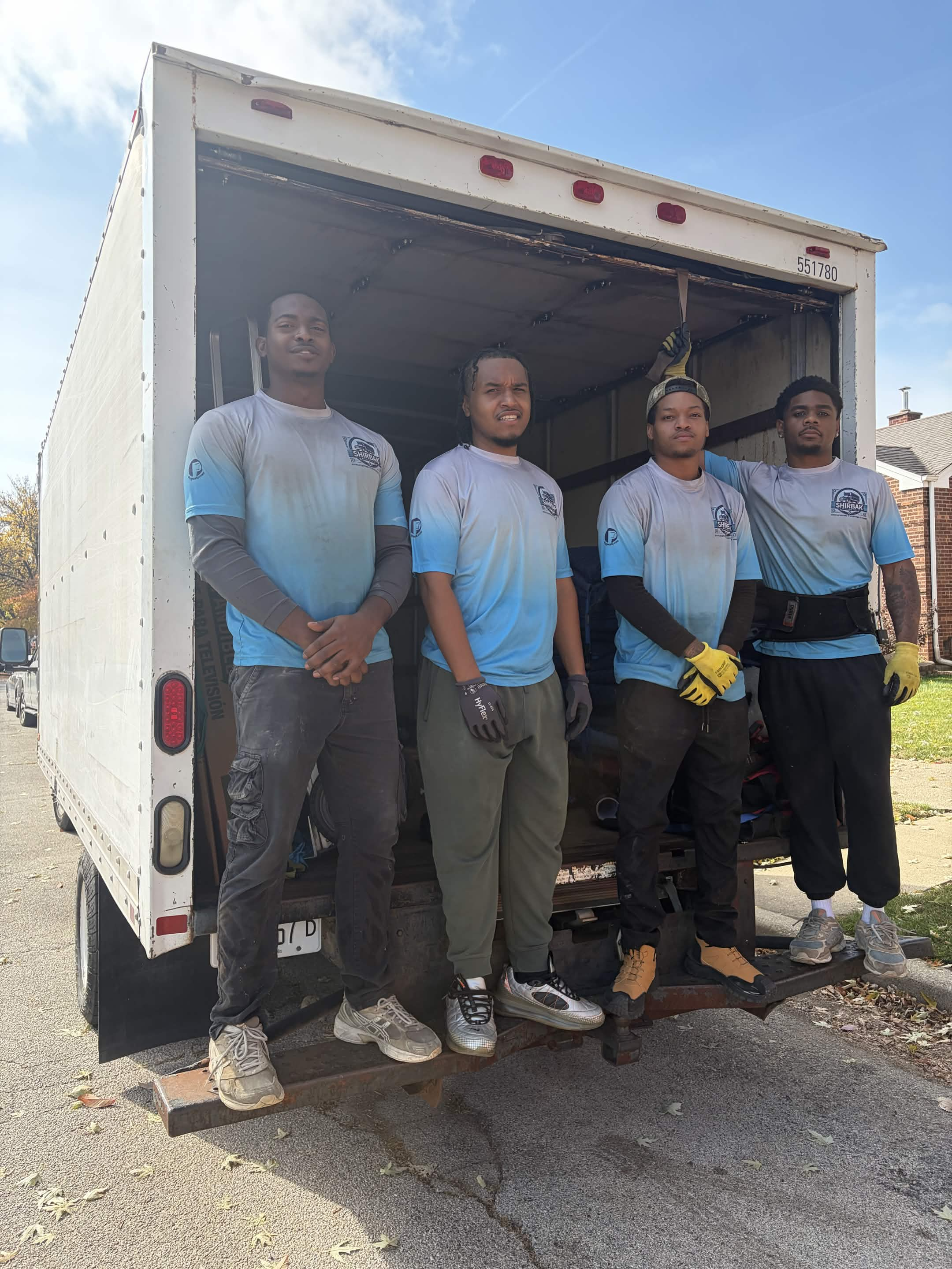 ShirBak crew standing at the open rear of their moving truck.