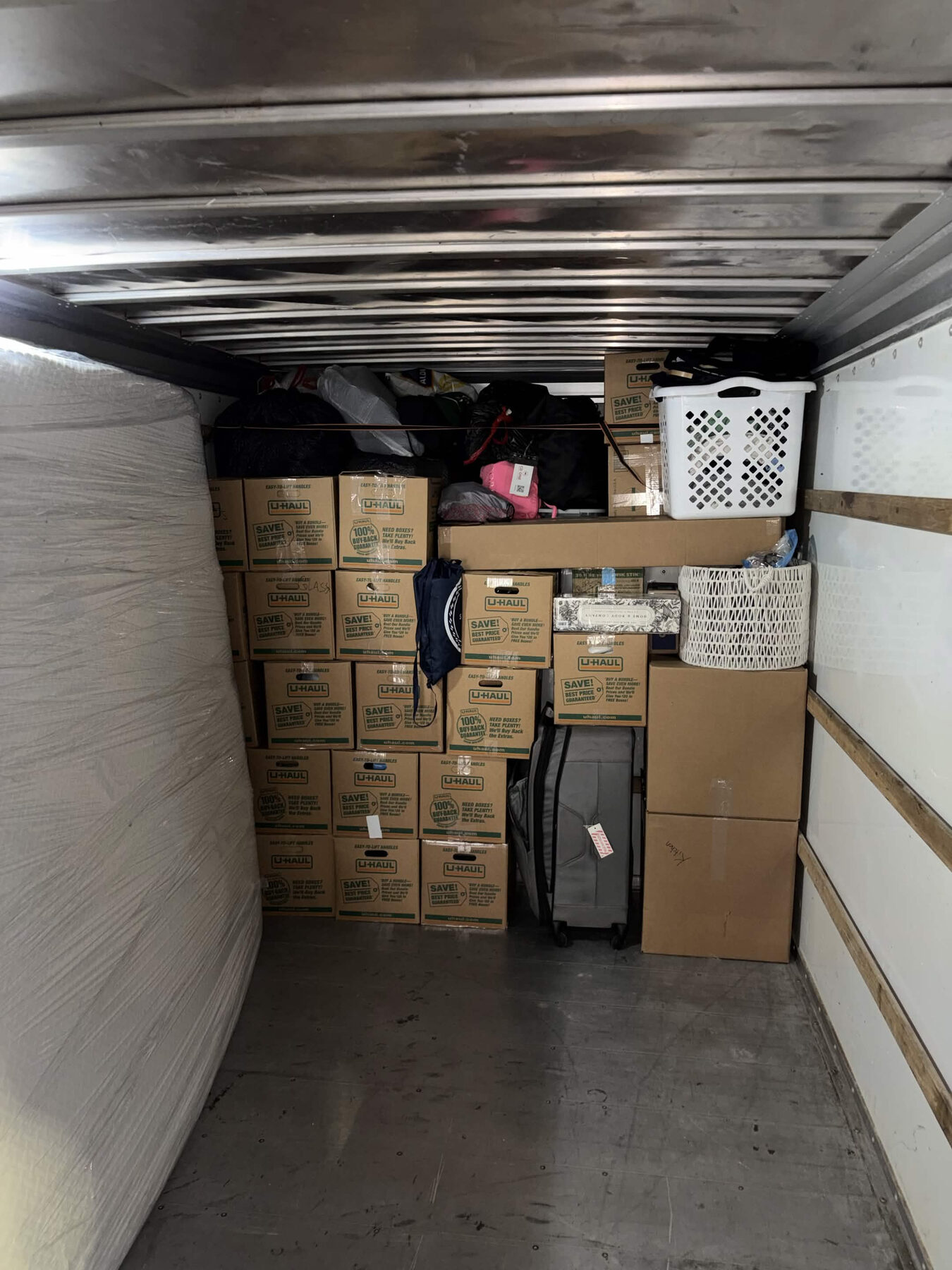 A rental truck packed with household belongings and a wrapped mattress.
