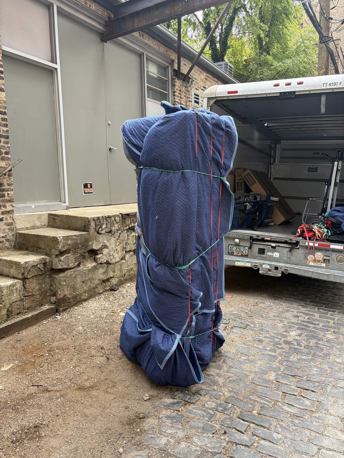 Wrapped furniture being moved from a building to a truck.